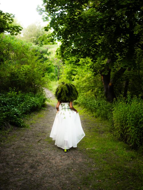 Free A woman in a white dress walks through a lush forest path, embracing nature. Stock Photo