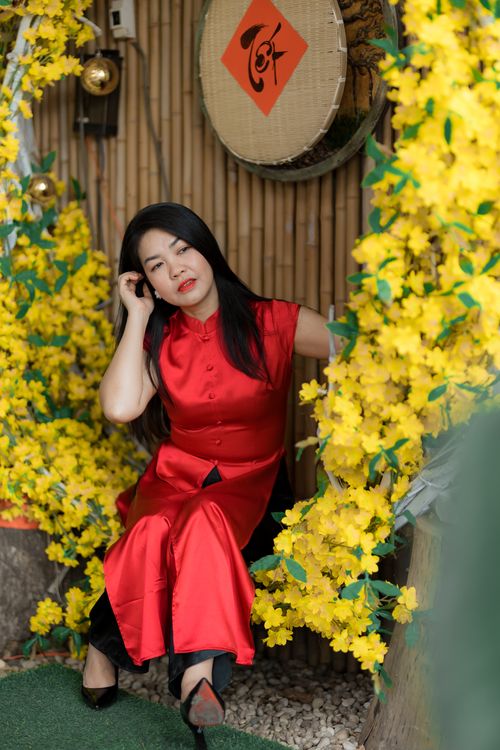 Free Asian woman in traditional red dress surrounded by vibrant yellow flowers, creating a festive and colorful scene. Stock Photo