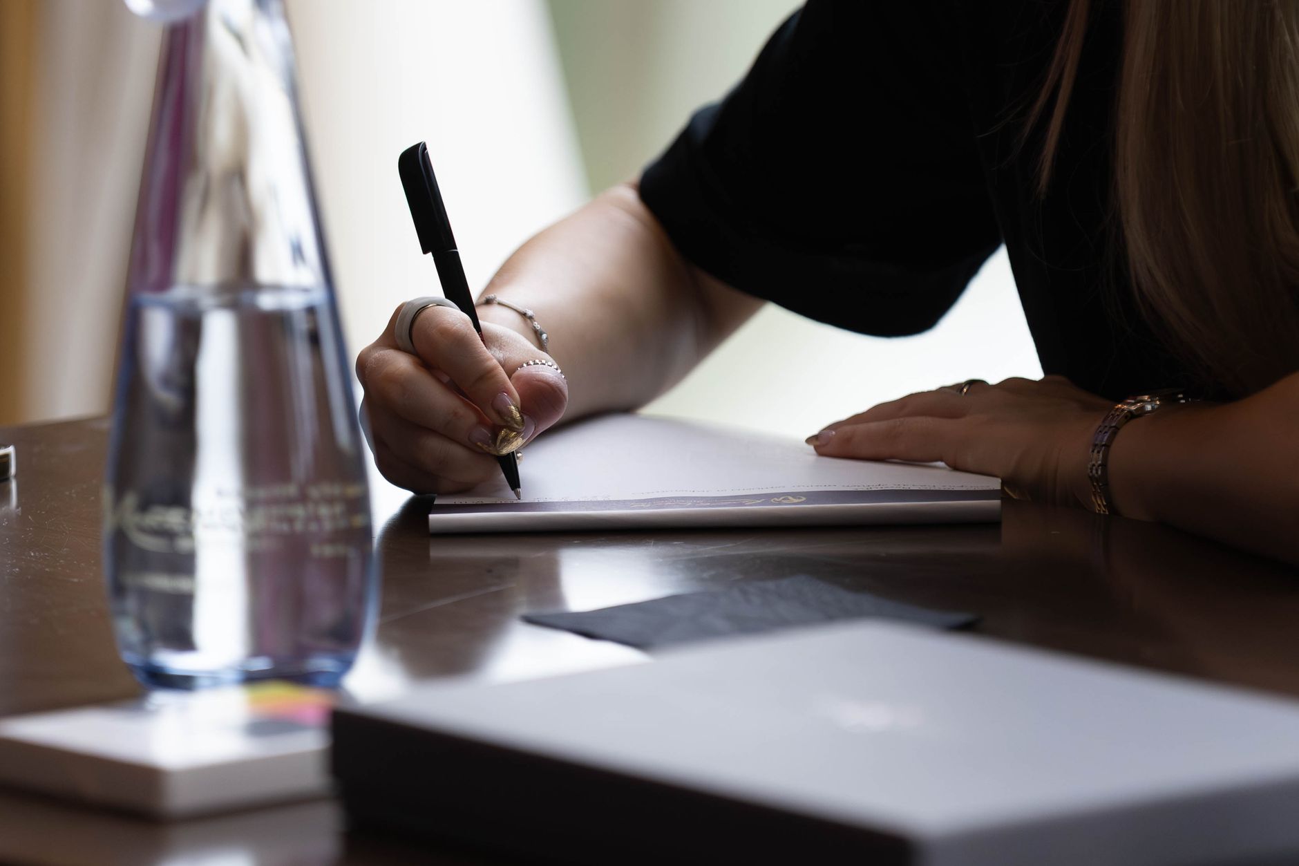 Close-up of a woman taking notes indoors with a pen and notebook. Ideal for business or education content.