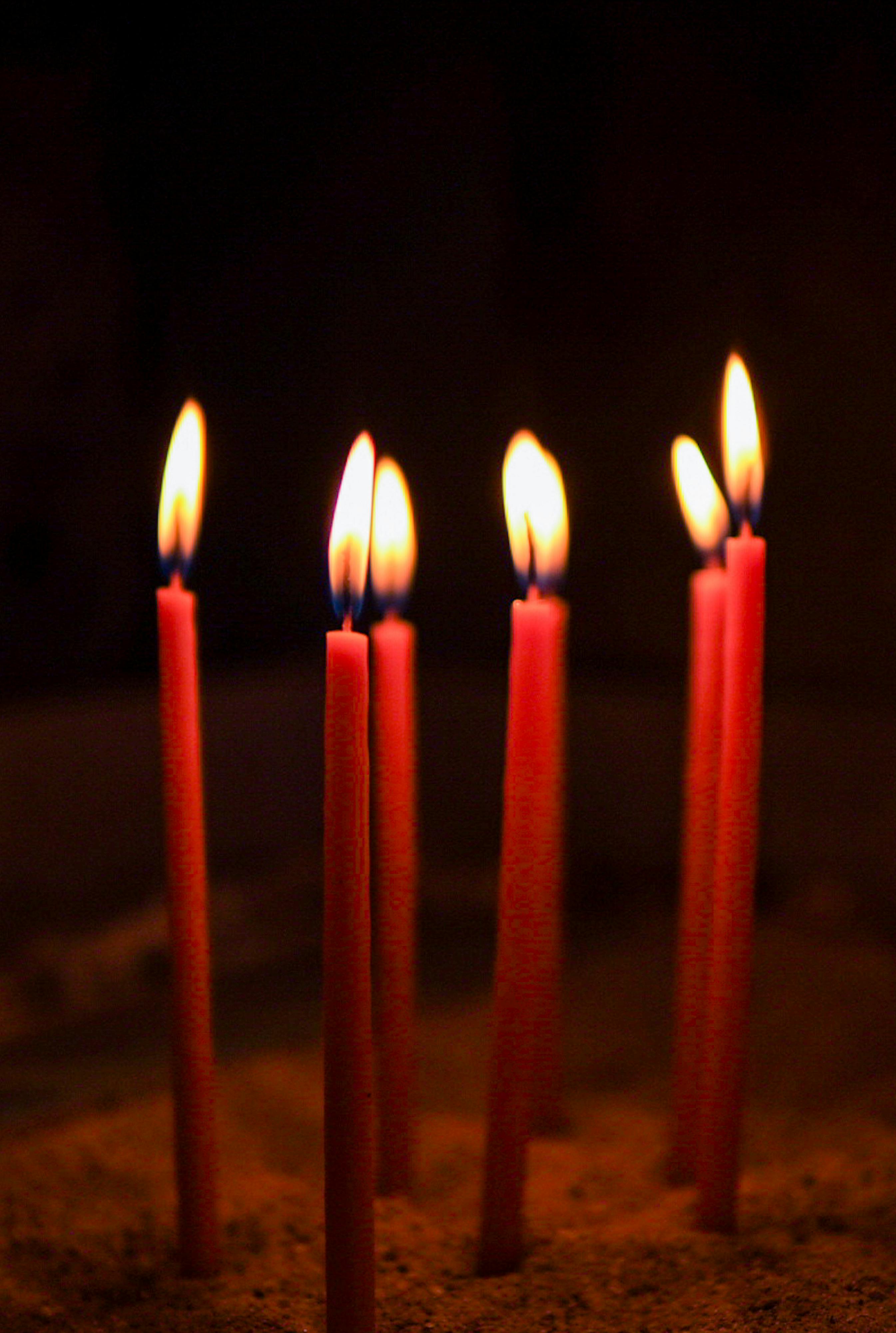 Vibrant red candles glow in a dark setting, capturing a serene and spiritual ambiance in İstanbul.