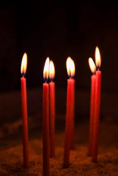 Vibrant red candles glow in a dark setting, capturing a serene and spiritual ambiance in İstanbul.