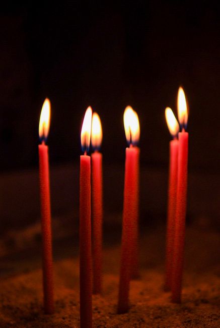 Vibrant red candles glow in a dark setting, capturing a serene and spiritual ambiance in İstanbul.