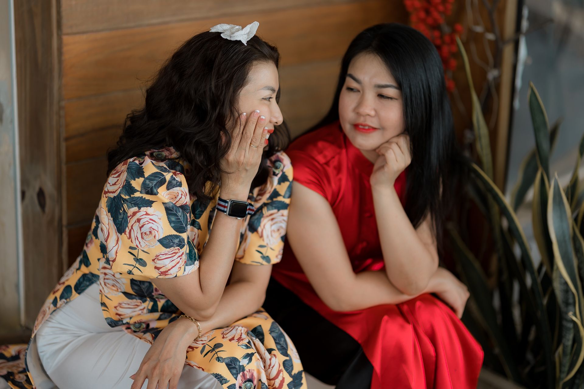 Two women in colorful outfits engaging in a friendly conversation indoors.