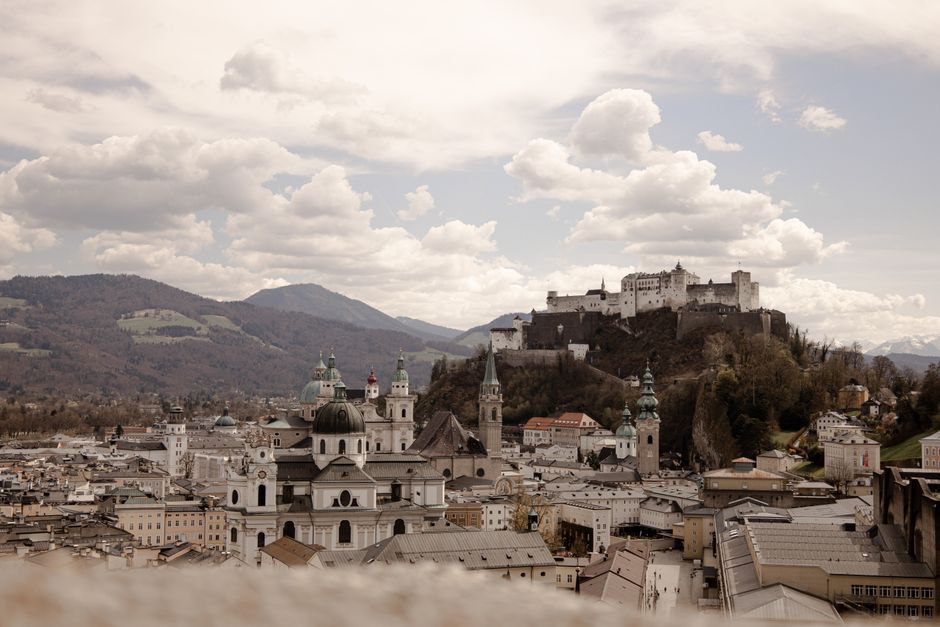 Discover the beauty of Salzburg with its historic architecture and the iconic Hohensalzburg Fortress under a cloudy sky.