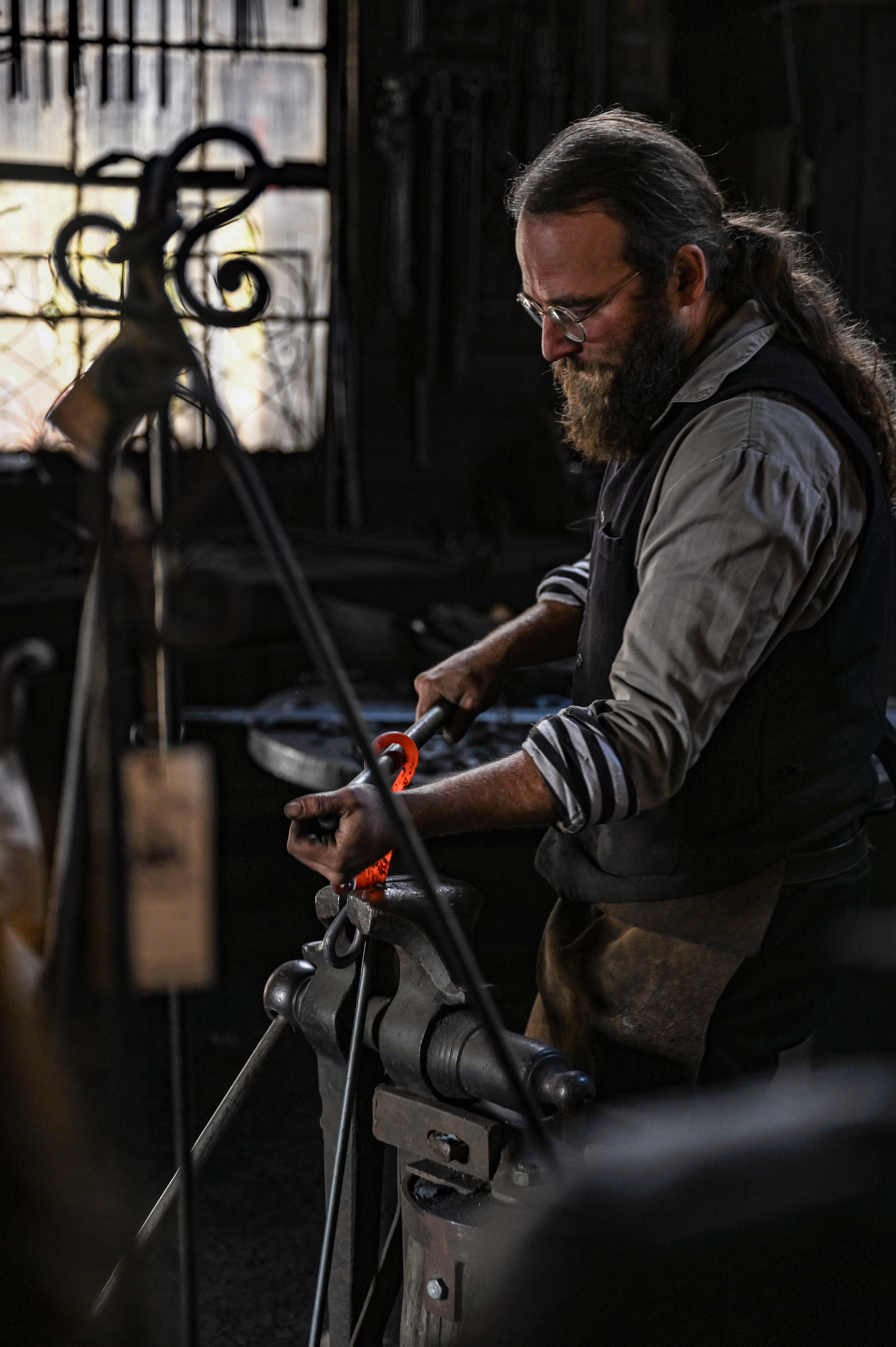 A focused blacksmith in a workshop shaping metal with precision and skill.