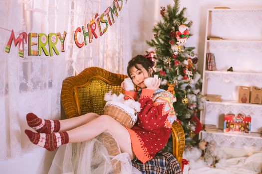 Young woman enjoying a cozy Christmas setting with festive decorations and a Christmas tree.