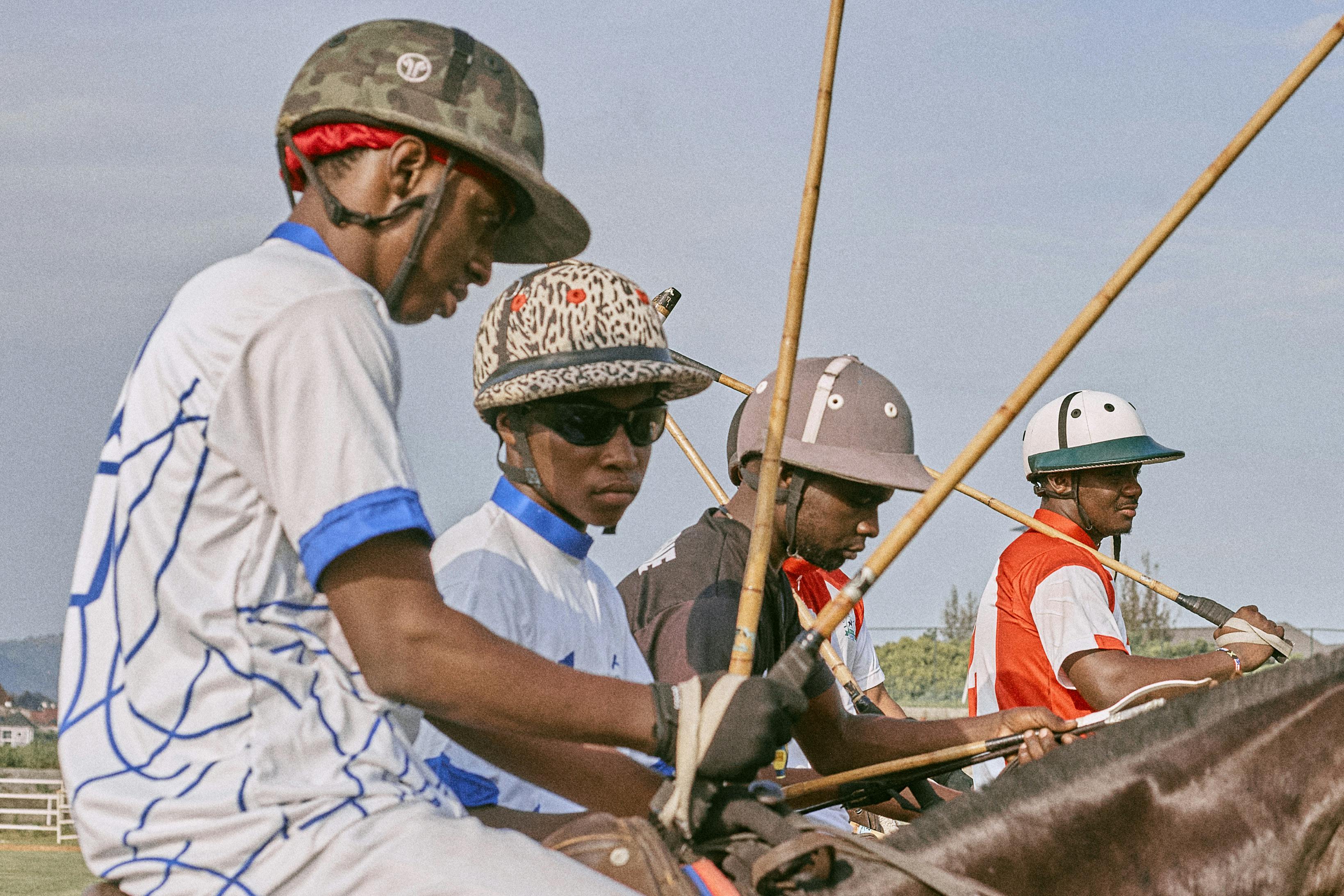 Four polo players on horseback, ready for a game on a sunny day.