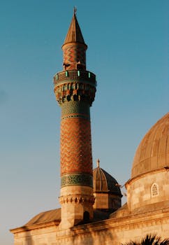 A beautifully patterned minaret captured at sunset with a clear blue sky.