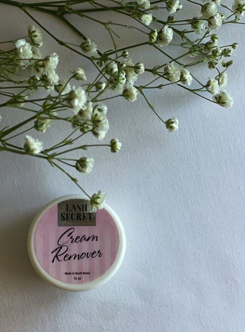 Free Elegant Lash Secret cream remover placed with delicate white flowers on a clean surface. Stock Photo
