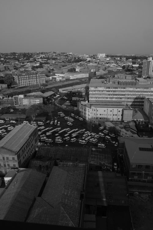 Free Black and white aerial view of a cityscape with buildings and parked vehicles. Stock Photo