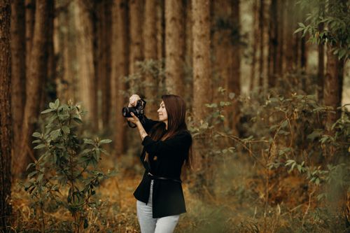 Free Woman photographer takes pictures in a tranquil autumn forest setting. Stock Photo
