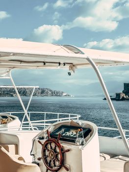 A serene yacht deck view overlooking a calm ocean and distant island under a sunny sky.