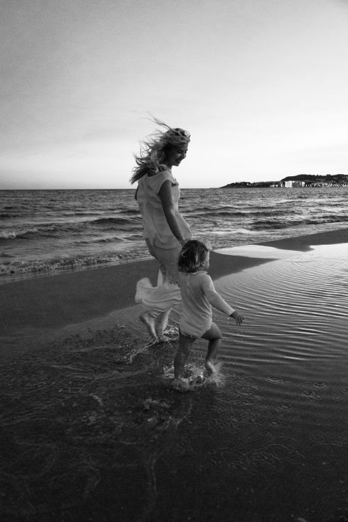 Free A mother and child joyfully playing on the beach during twilight. Black and white photograph. Stock Photo