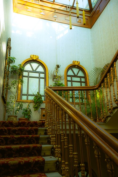 Free Luxurious interior staircase adorned with plants, gold accents, and natural light. Stock Photo