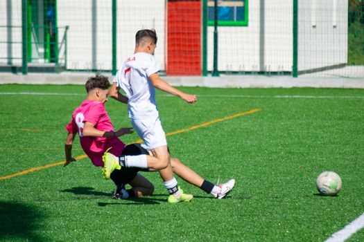 Dynamic action shot of teenage soccer players tackling during a match on a sunny day.