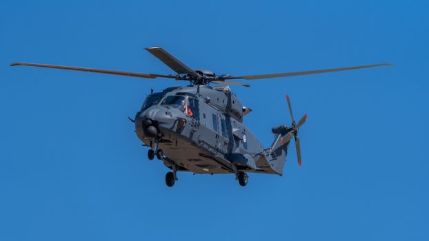 An NH90 military helicopter flying against a bright, clear blue sky in Los Llanos, España.
