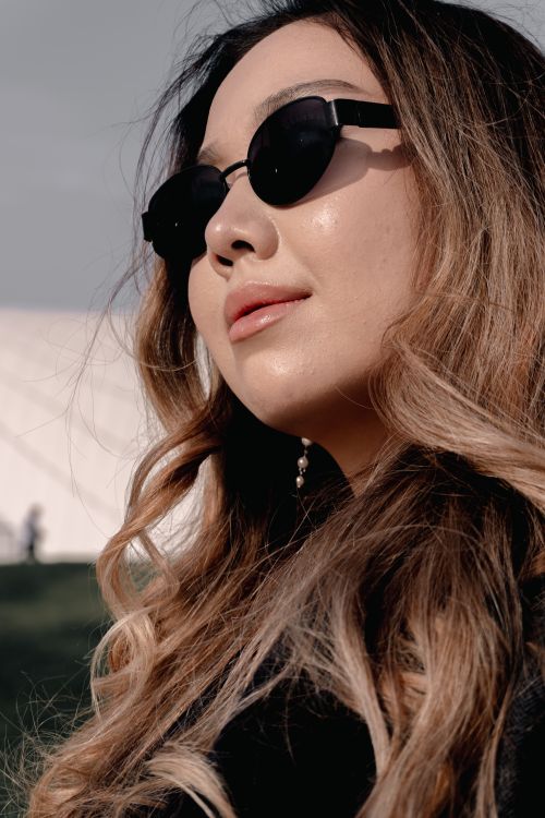 Free Portrait of a woman in sunglasses enjoying a sunny day outdoors, showing style and confidence. Stock Photo