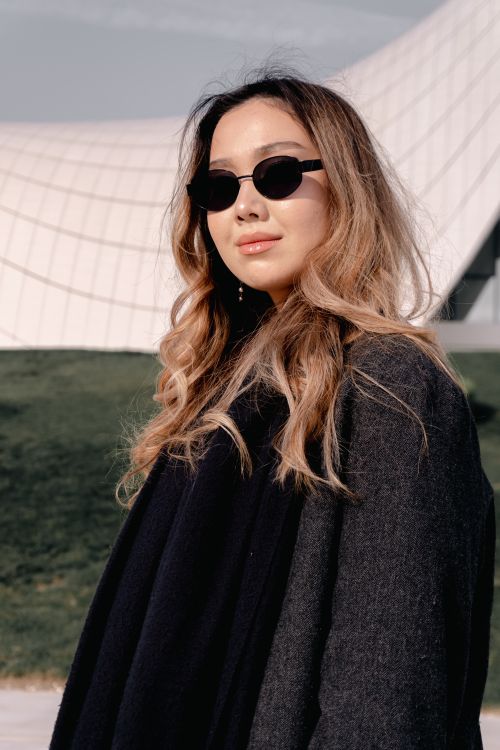 Free Stylish woman with sunglasses in a coat outdoors, modern architecture background. Stock Photo