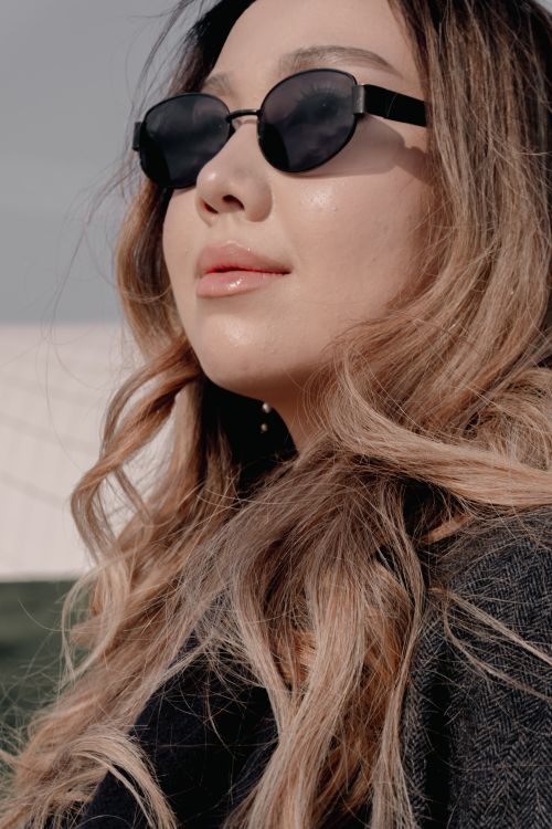 Free Close-up of a woman in sunglasses with flowing hair, exuding style and confidence. Stock Photo