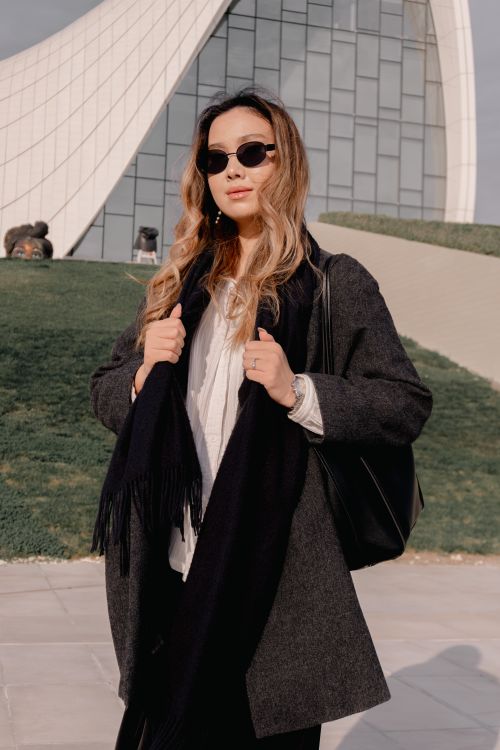 Free Elegant woman in sunglasses posing confidently near a modern architectural building. Stock Photo