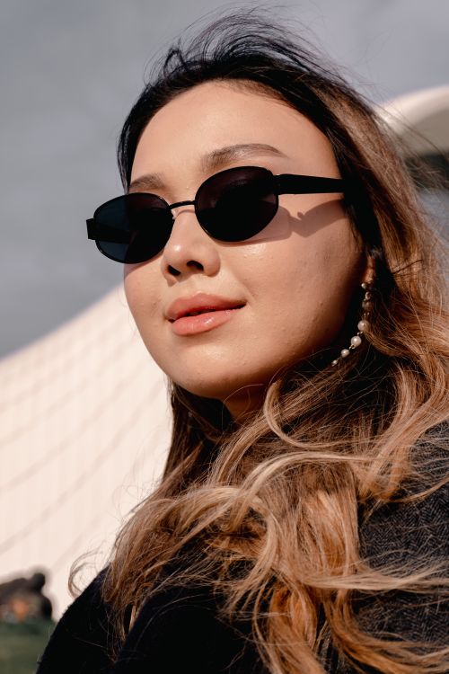 Free A trendy woman wearing sunglasses poses under bright daylight, exuding modern style. Stock Photo