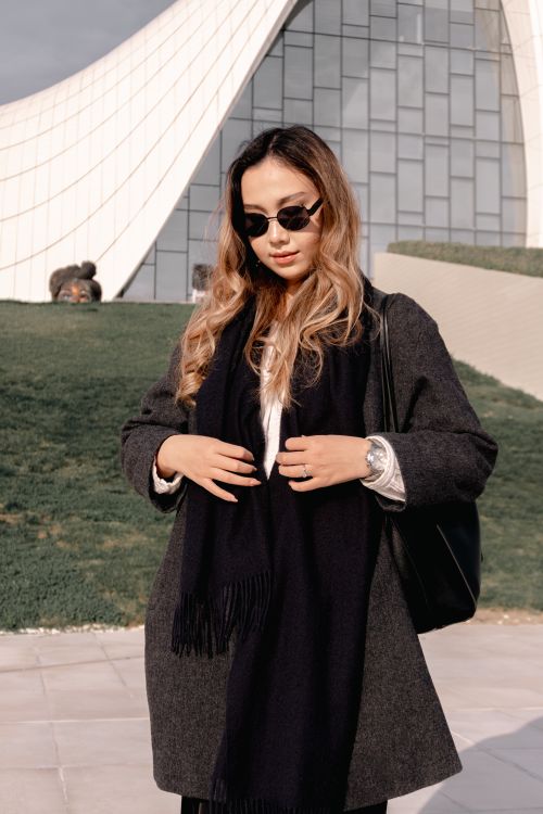 Free Fashionable woman in sunglasses standing outside modern architectural building with unique design. Stock Photo