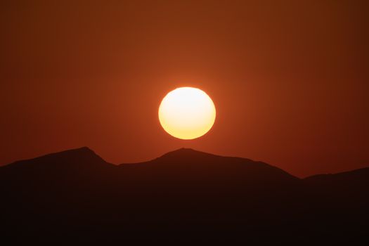 Beautiful sunrise captured over the mountains in Tirol, Austria, showcasing a vibrant orange sky.