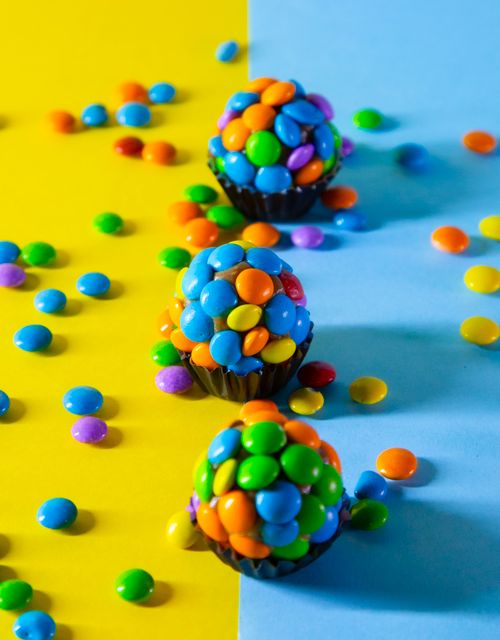 Free Vibrant Brazilian candy truffles covered in colorful chocolate pieces on a yellow and blue backdrop. Stock Photo