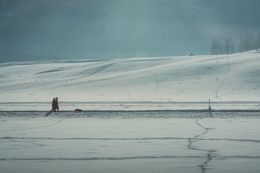 A tranquil winter landscape with a couple walking through snowy fields in Schladming, Austria.