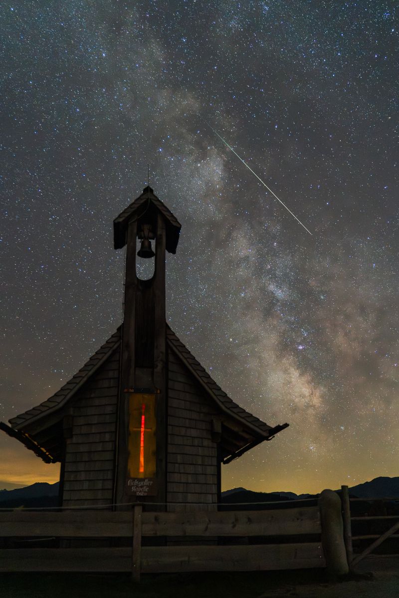 A serene chapel beneath a starry sky in Wildschönau, Austria, with the Milky Way overhead.