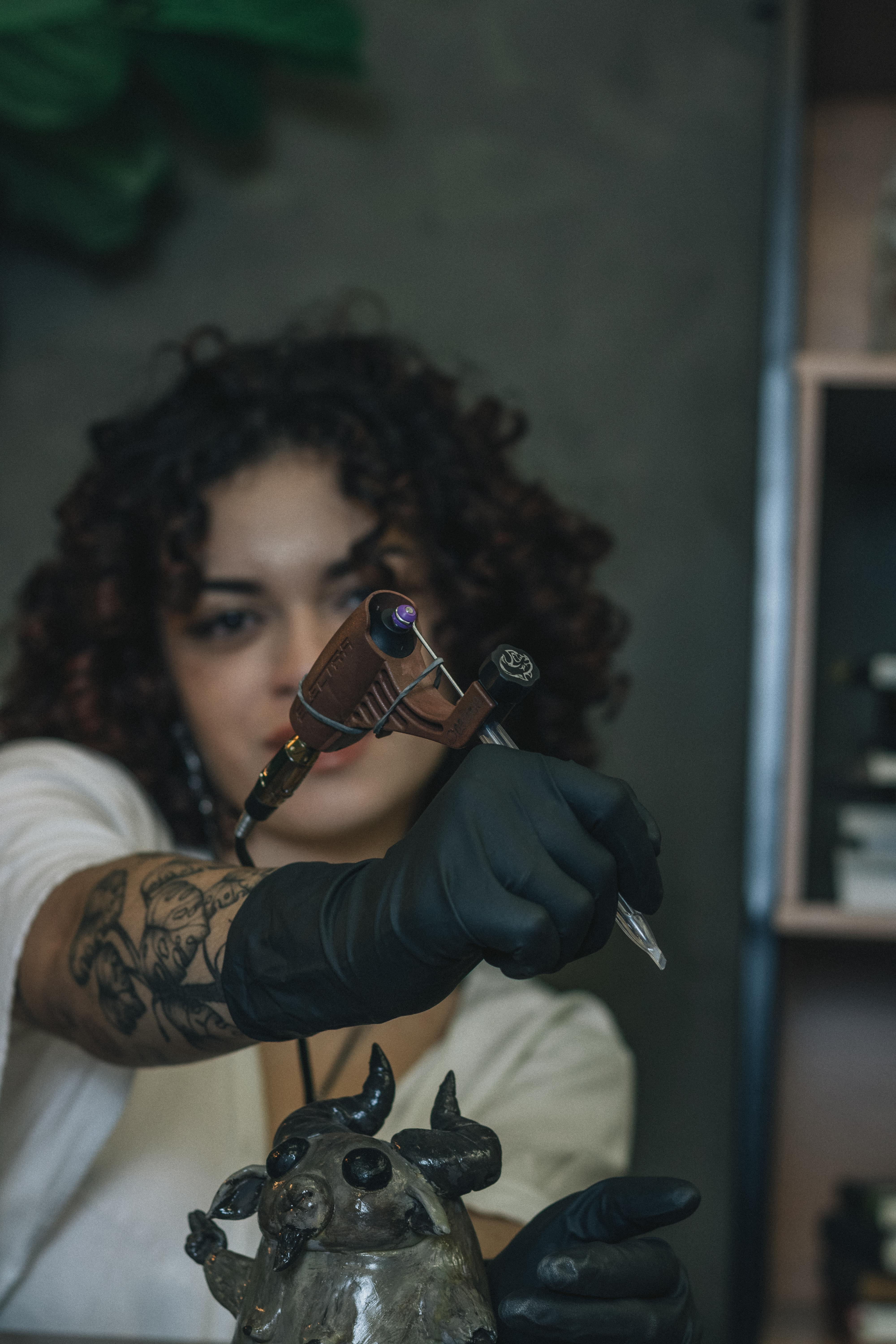 Gratis Tatovør holder en tatoveringsmaskine og viser indviklede armtatoveringer indendørs. Lagerfoto