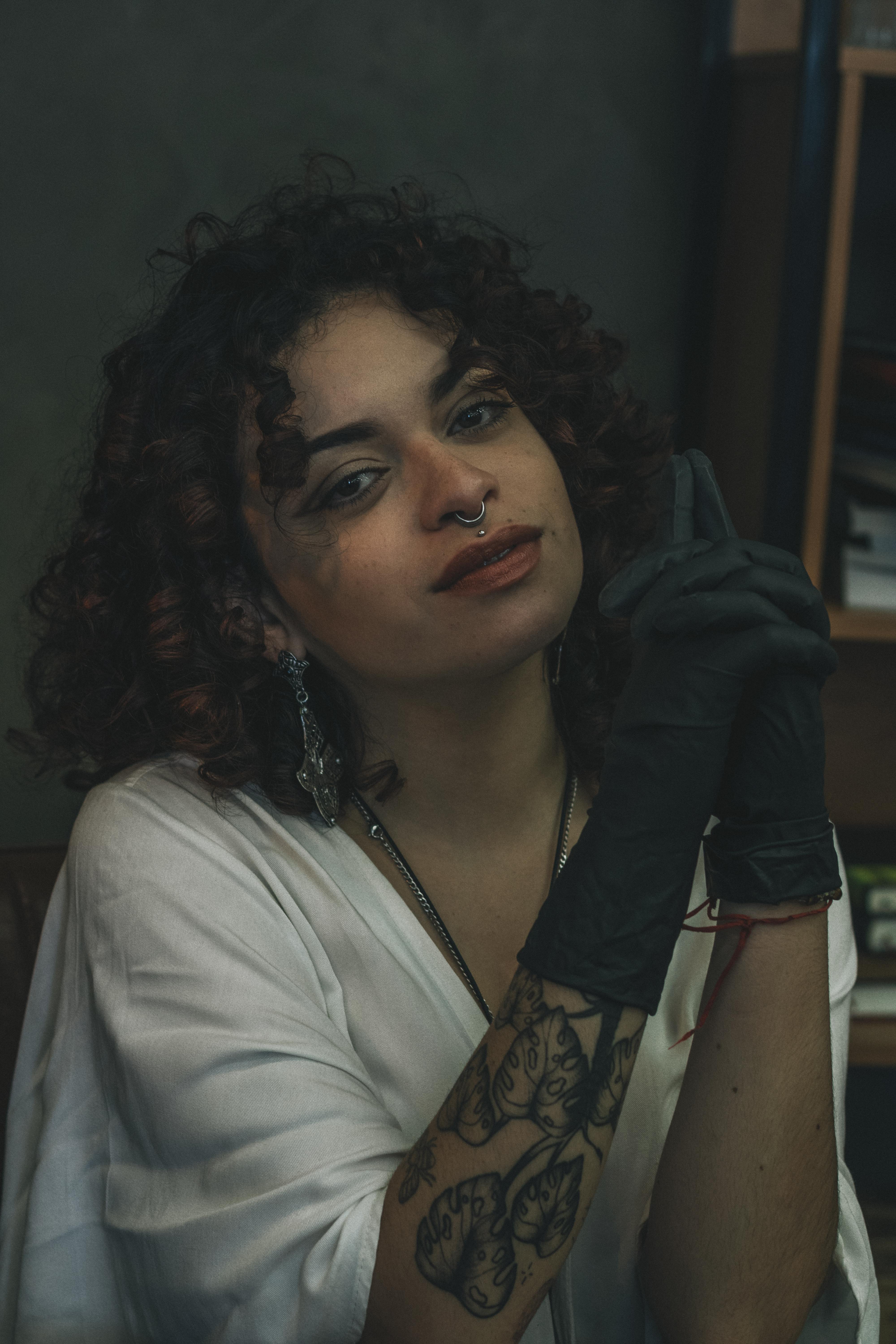 ingyenes Portré egy stílusos nőről tetoválásokkal és orrkarikával, fehér ingben és fekete kesztyűben. Stockfotó