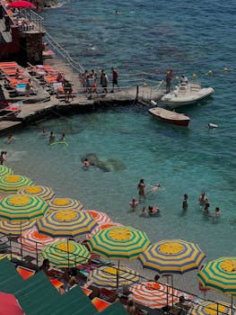 Lively beach view with colorful umbrellas and people enjoying the water in Positano, Italy.