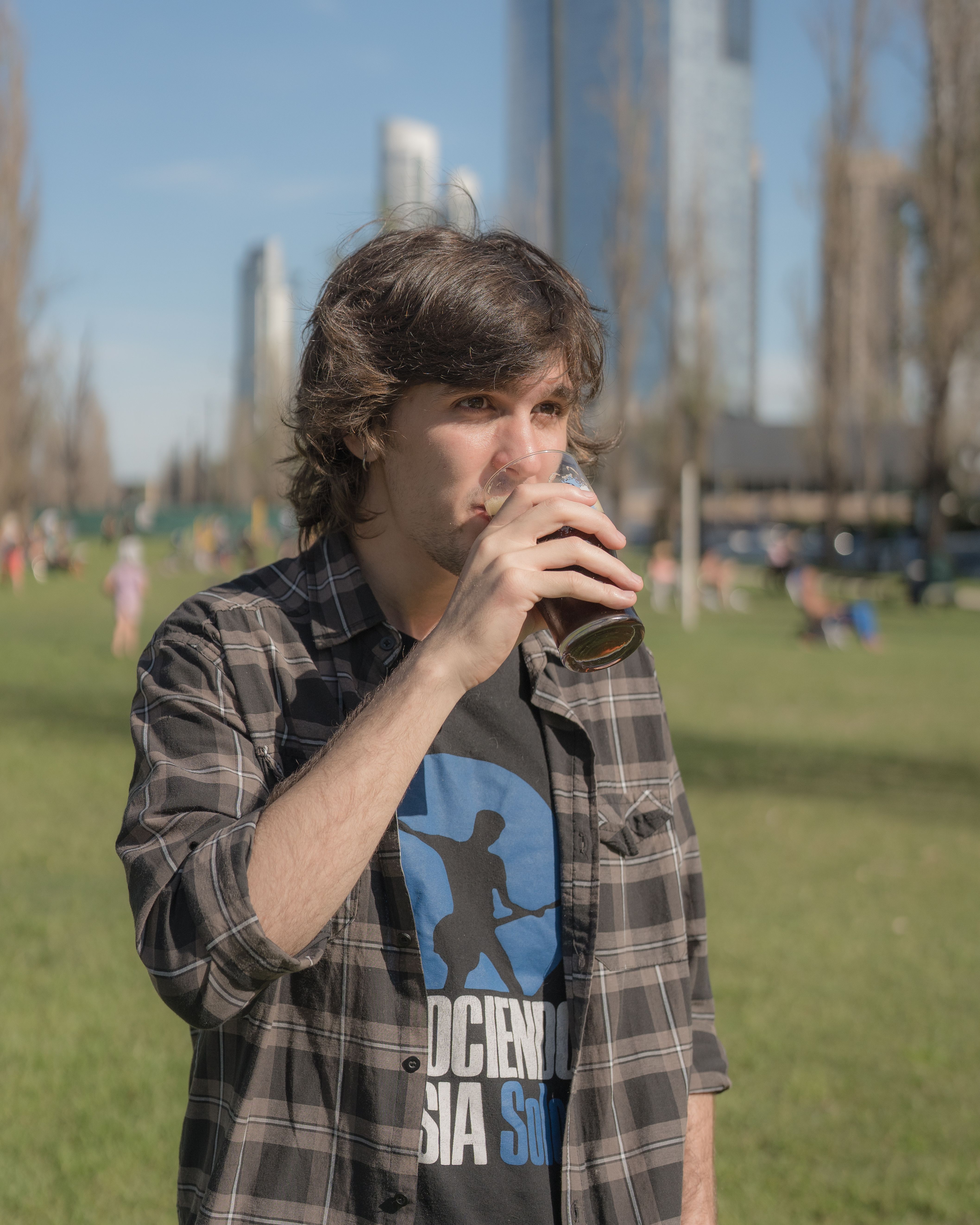 Casual young man enjoying a mate drink in a Buenos Aires park during a sunny day.