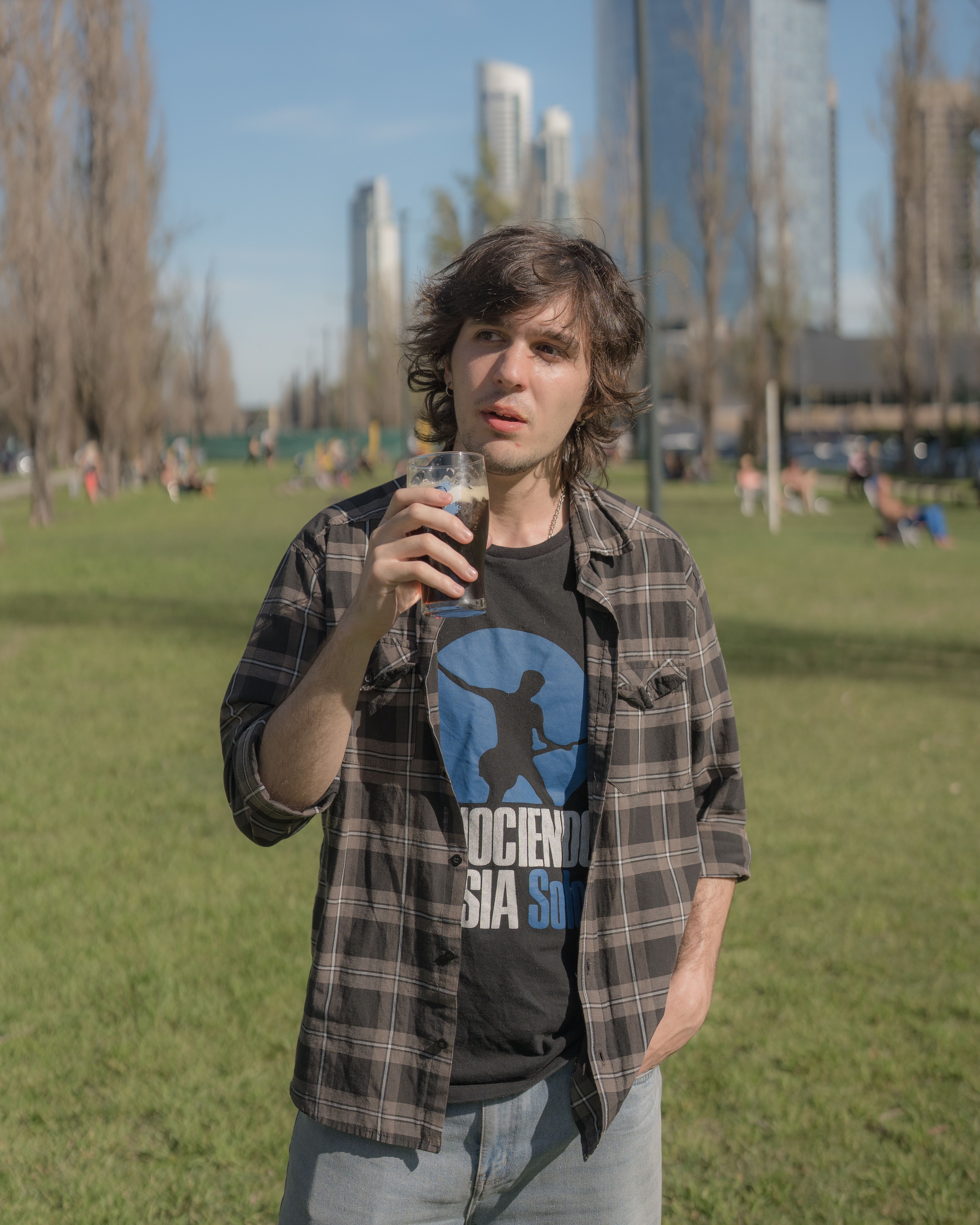 Man enjoying a drink in a Buenos Aires park on a sunny day.