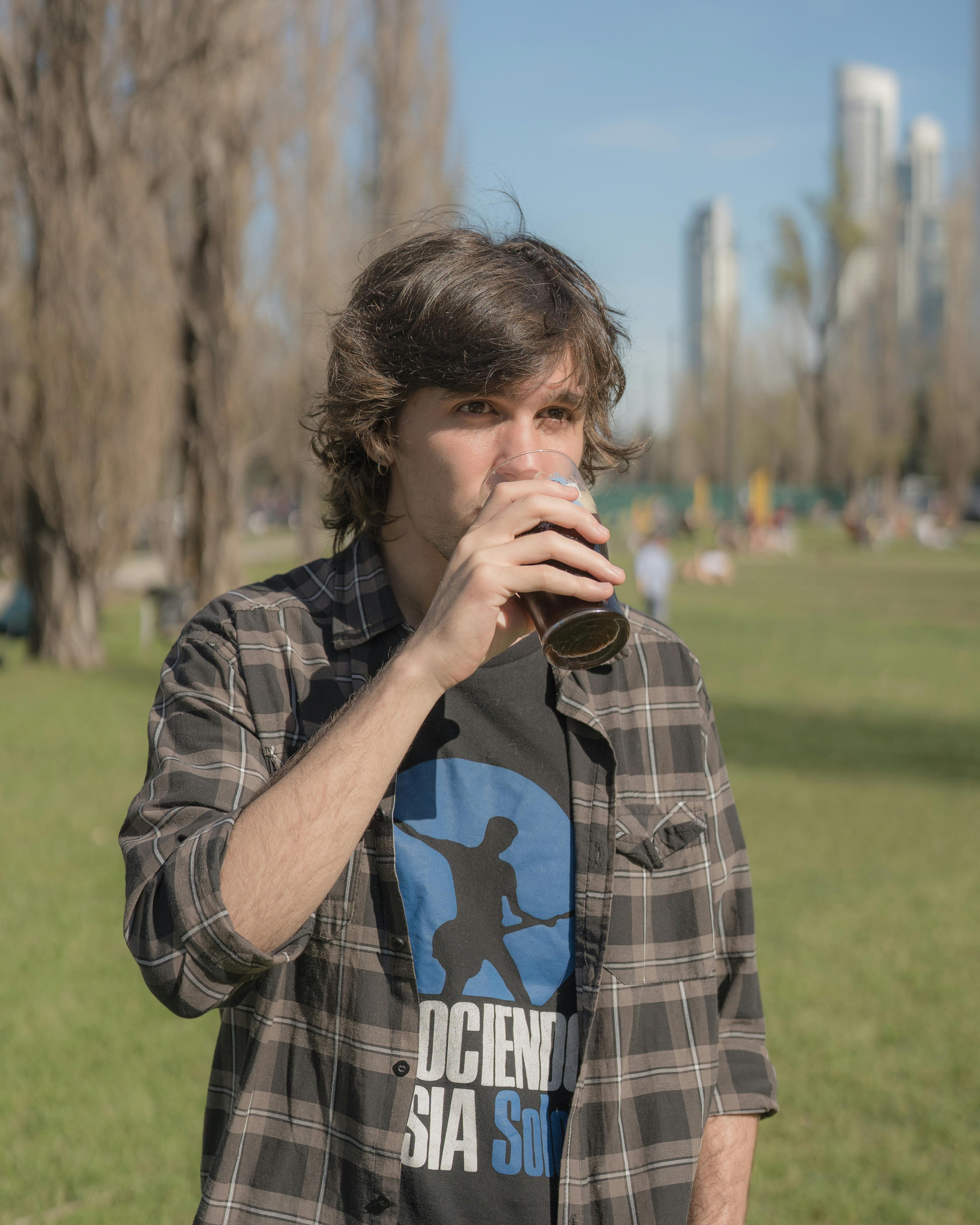 A young man drinks yerba mate in a Buenos Aires park on a sunny day.