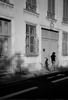 A person walks past classic French architecture on a sunny day in Nancy.