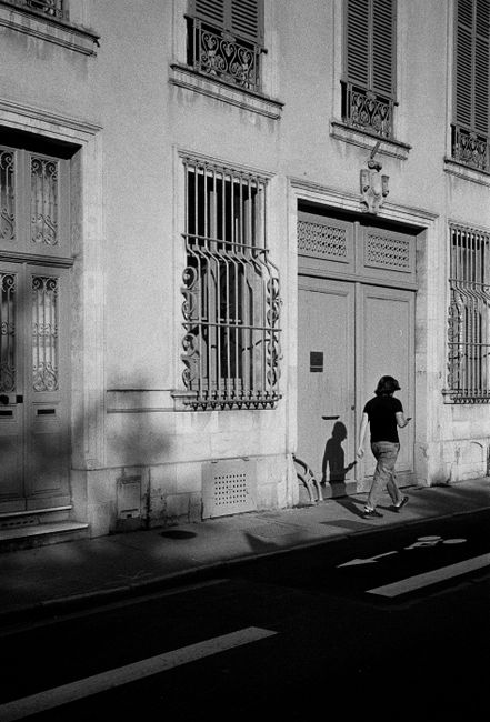 A person walks past classic French architecture on a sunny day in Nancy.
