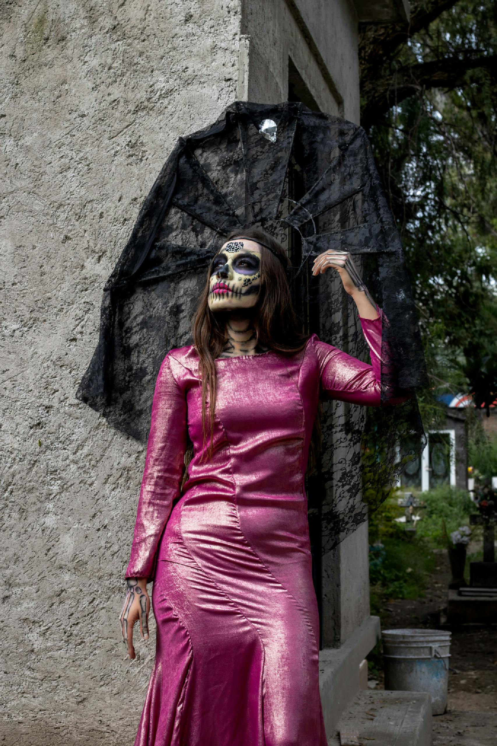 Woman in vibrant dress with skull makeup celebrating Day of the Dead.
