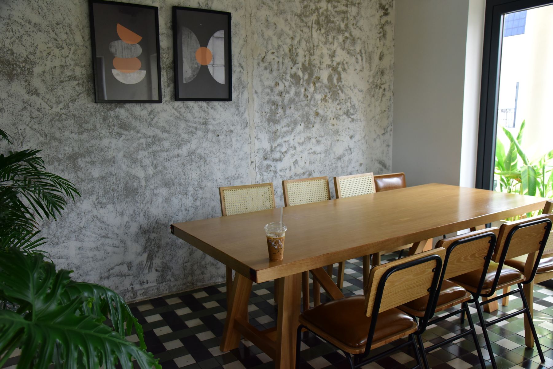 A warm waiting room with a long wooden table, chairs and framed prints