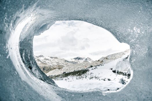 Captivating view of snowy mountains through an ice cave in Graubünden, Switzerland.