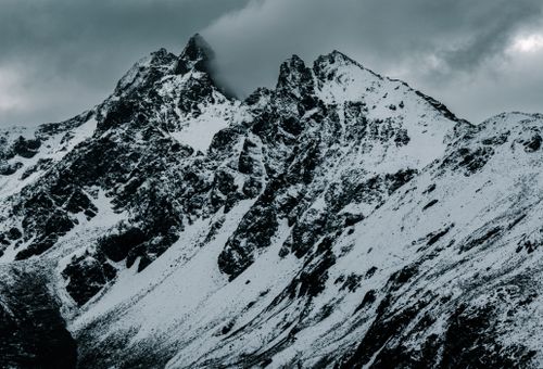 Free Majestic snow-covered mountains under cloudy skies in Graubünden, Switzerland. Stock Photo