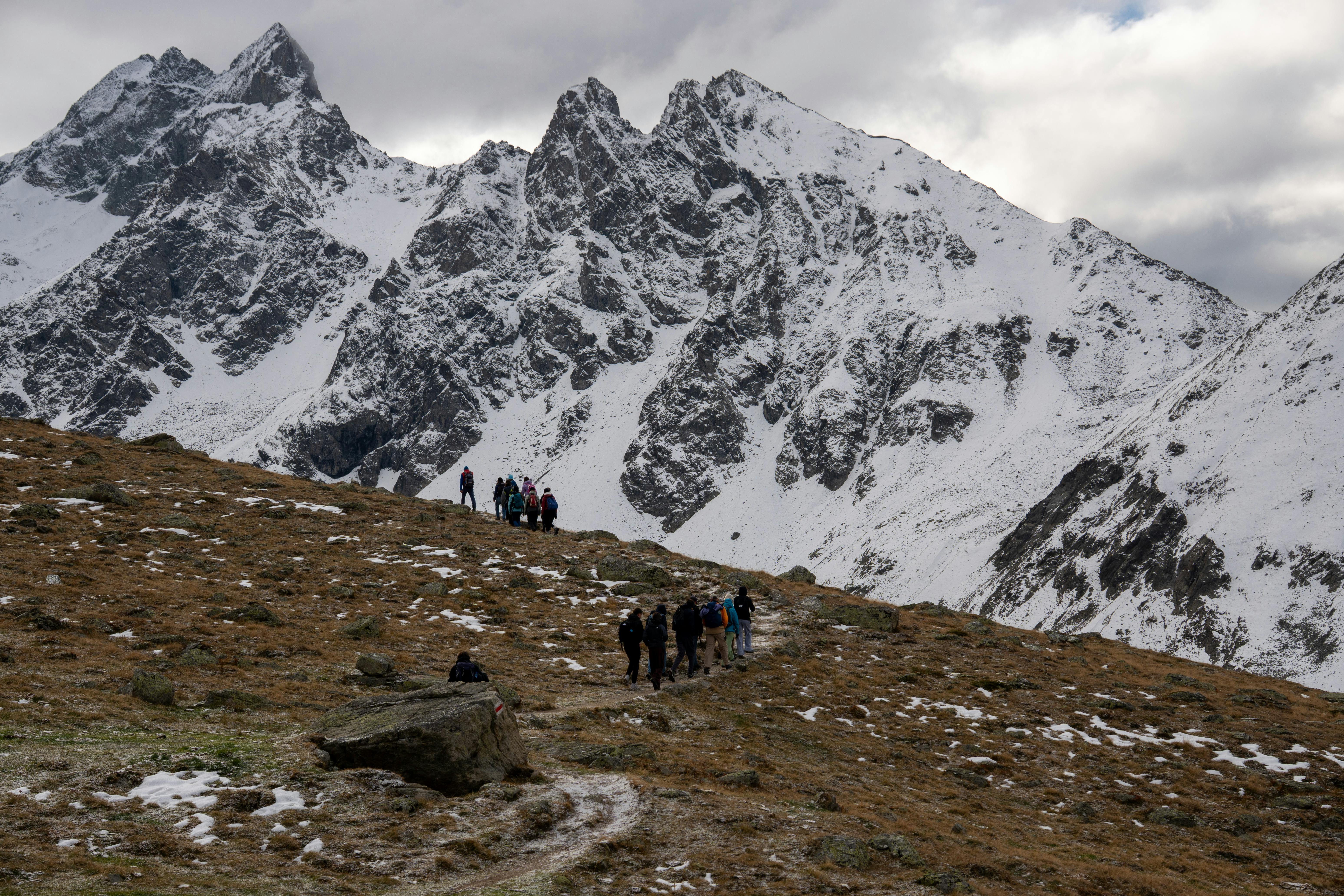 Group of hikers traversing snowy terrain in the Swiss Alps with stunning mountain views.