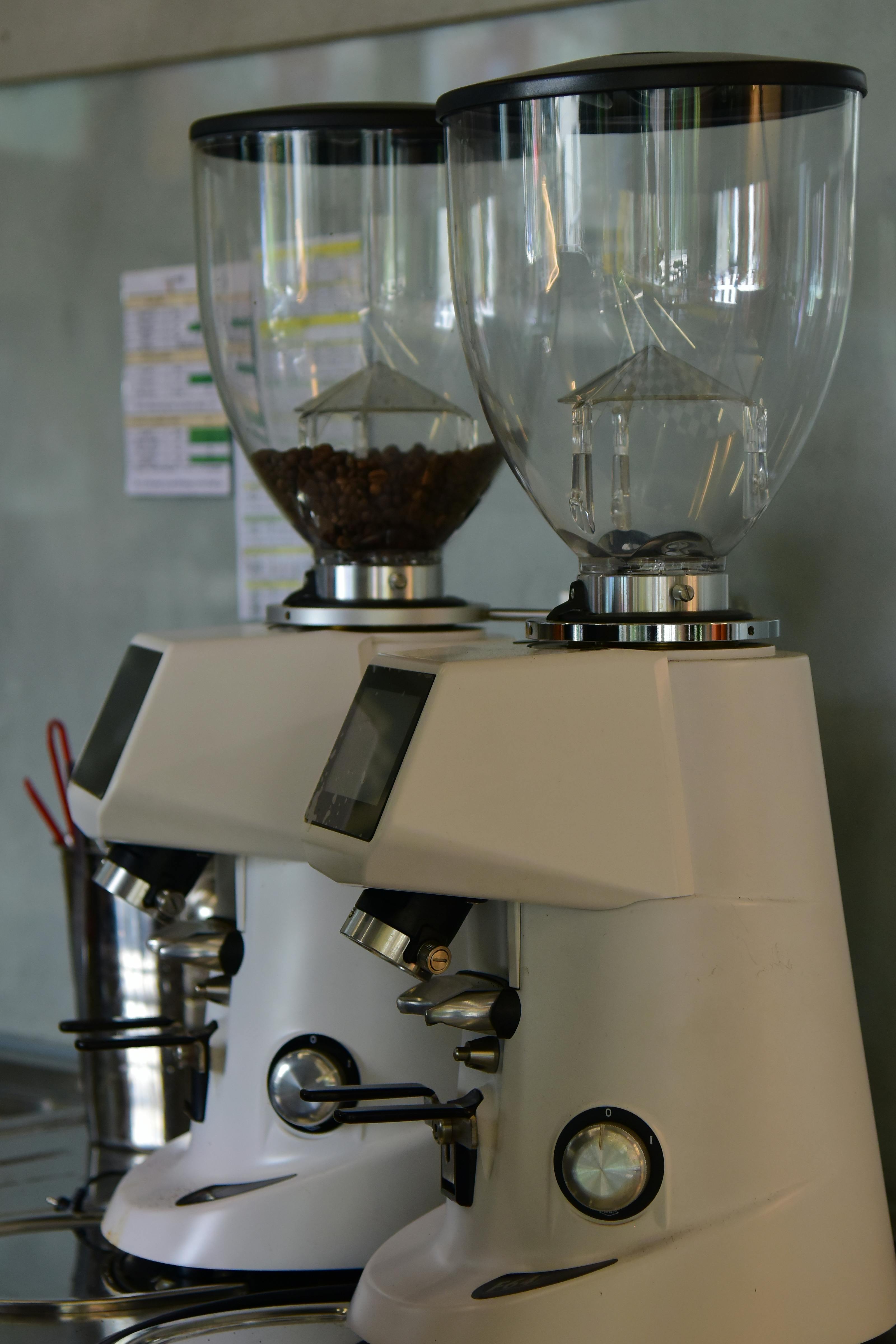 Two coffee grinders in a cafe with bean hoppers