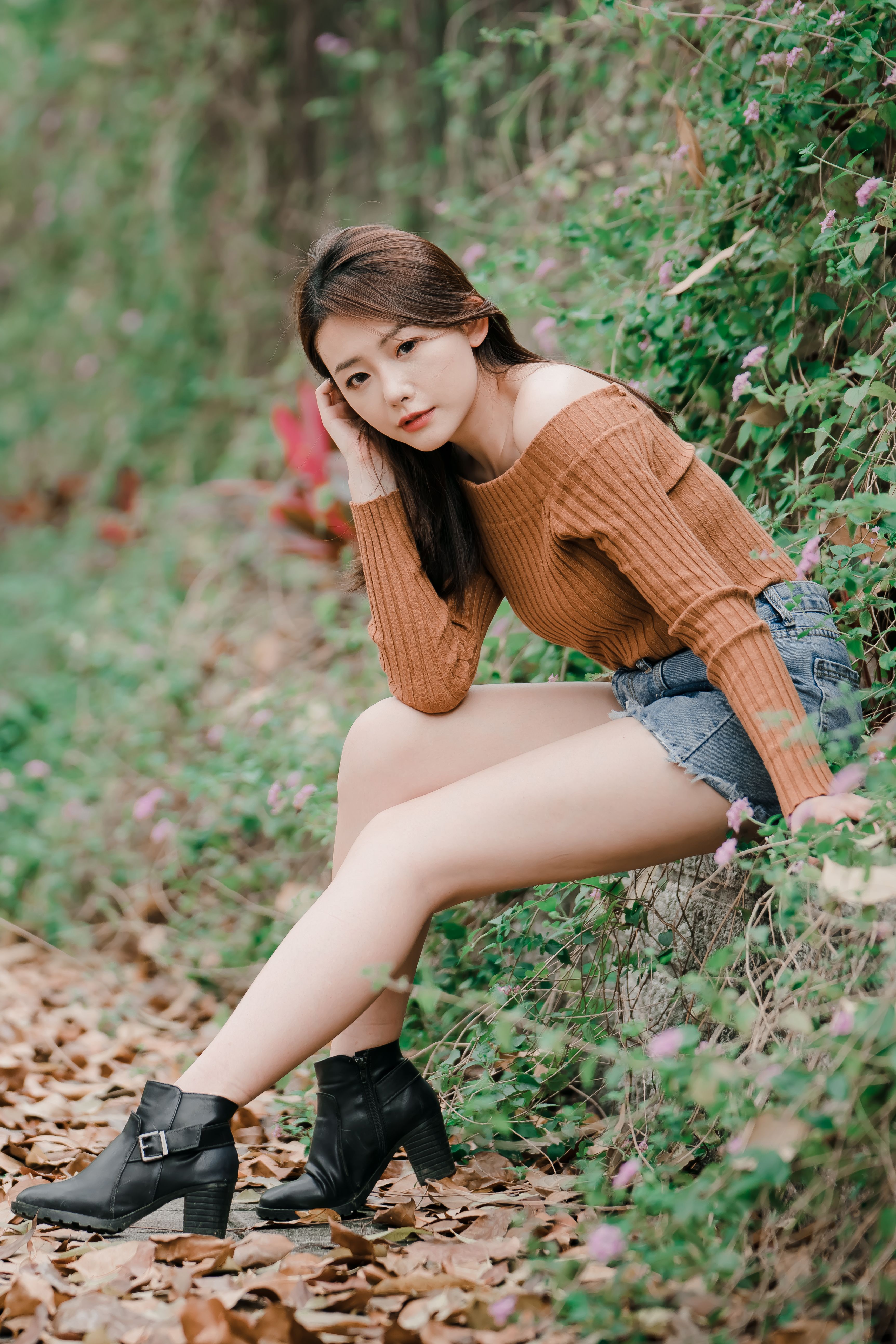 A fashionable woman posing in a natural setting, showcasing autumn style and beauty.