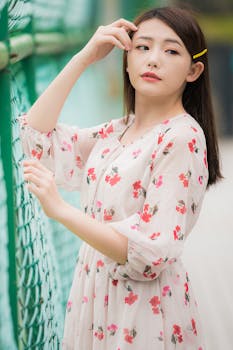 一位身穿花卉连衣裙的年轻女子在户外绿色栅栏旁的肖像