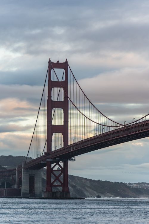 Free Scenic view of the Golden Gate Bridge against a cloudy sky, captured at sunset in San Francisco. Stock Photo