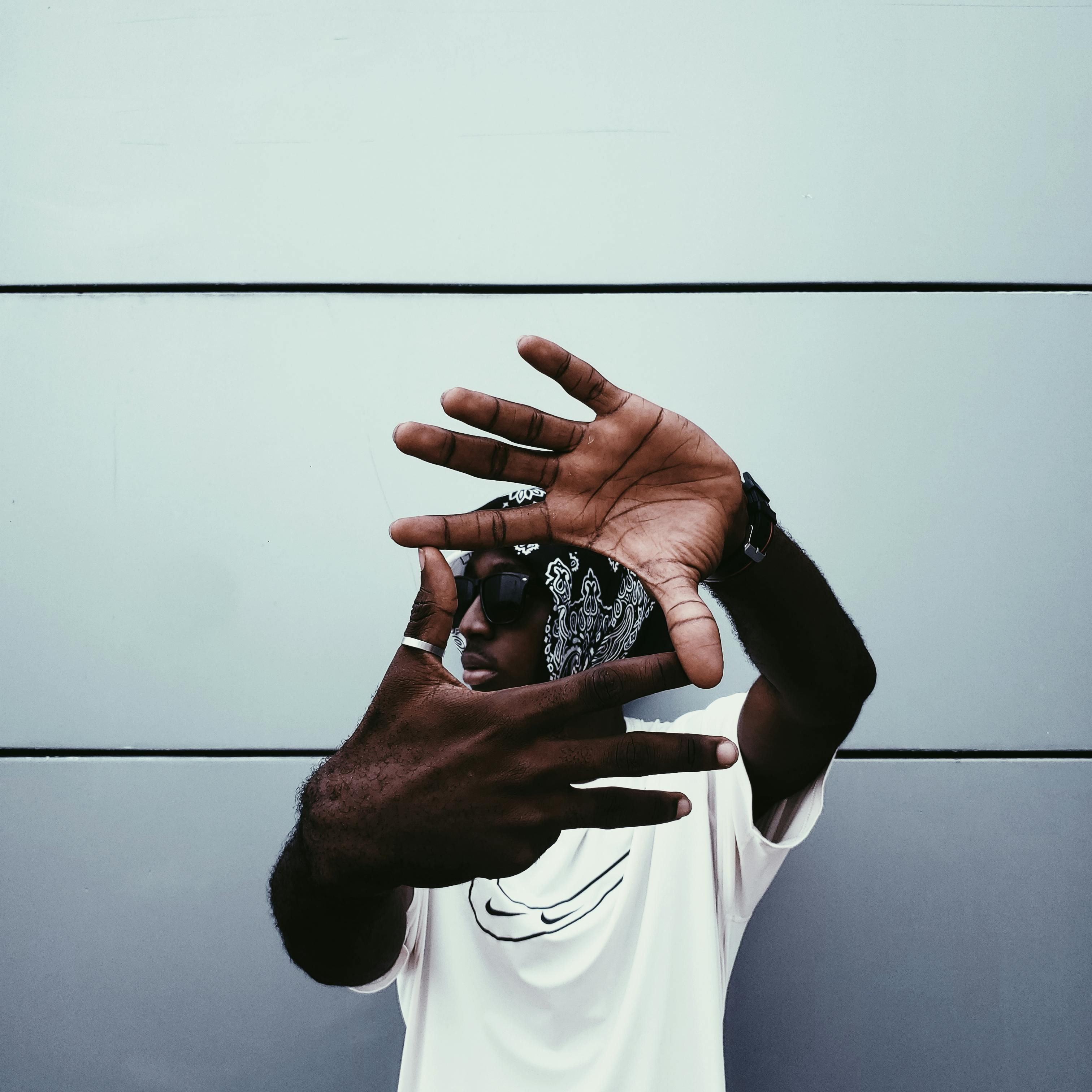 Fashionable person using hands to create a frame, stylish background.