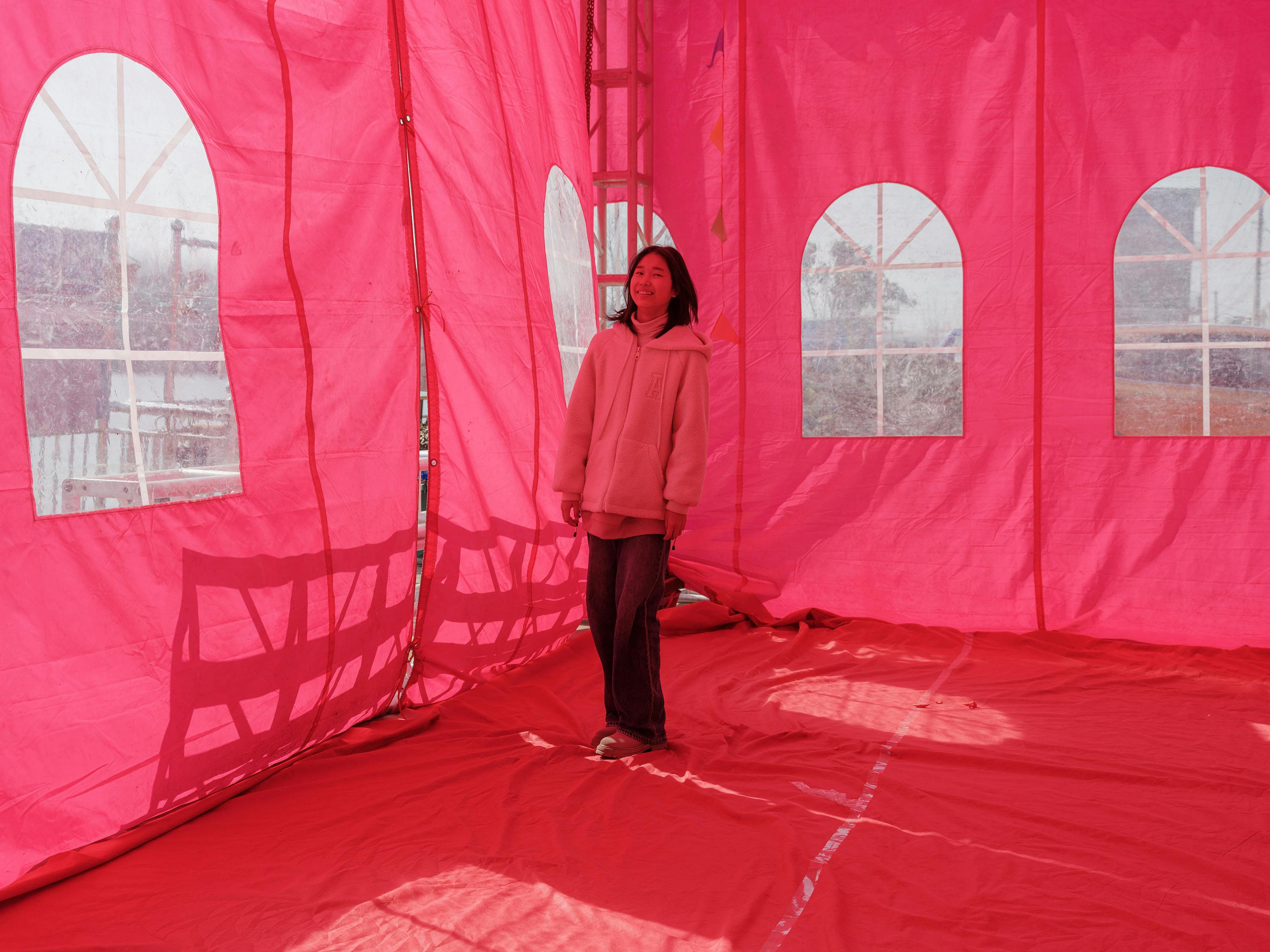 Gratuit O tânără stă în interiorul unui cort roz puternic luminat, creând o atmosferă veselă. Fotografie de stoc