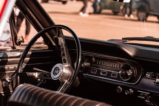 Close-up view of a vintage car interior focusing on the retro steering wheel and dashboard design.